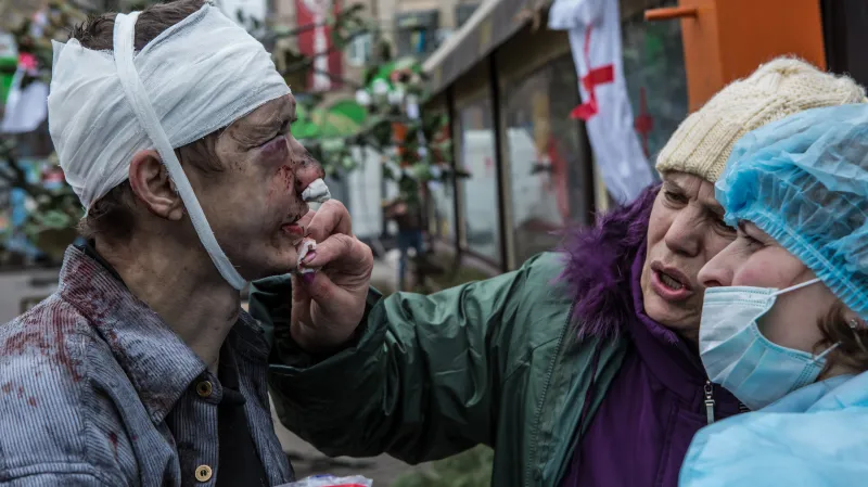 Zraněný demonstrant v péči zdravotníků v ulicích kolem náměstí Nezávislosti