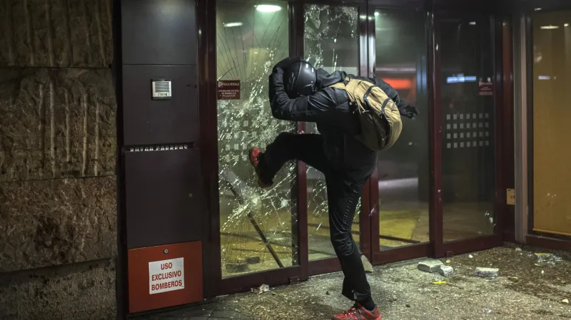 Demonstrant rozbíjí vstupní dveře banky