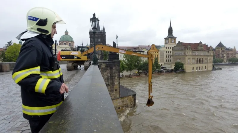Bagr odklízí naplaveniny na uzavřeném Karlově mostě