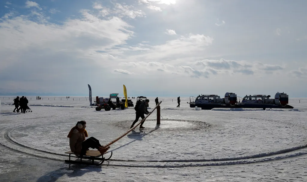 Lidé si užívají příznivého počasí na zamrzlém jezeře Bajkal v blízkosti sibiřské vesnice Listvjanka