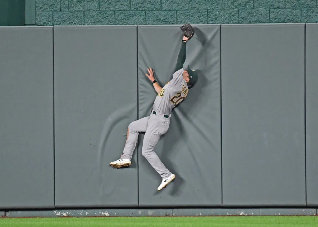 Oaklandský centr Mark Canha neusíná na žíněnce, ale dokončuje skok za baseballovým míčkem na Kauffmanově stadionu v Kansasu