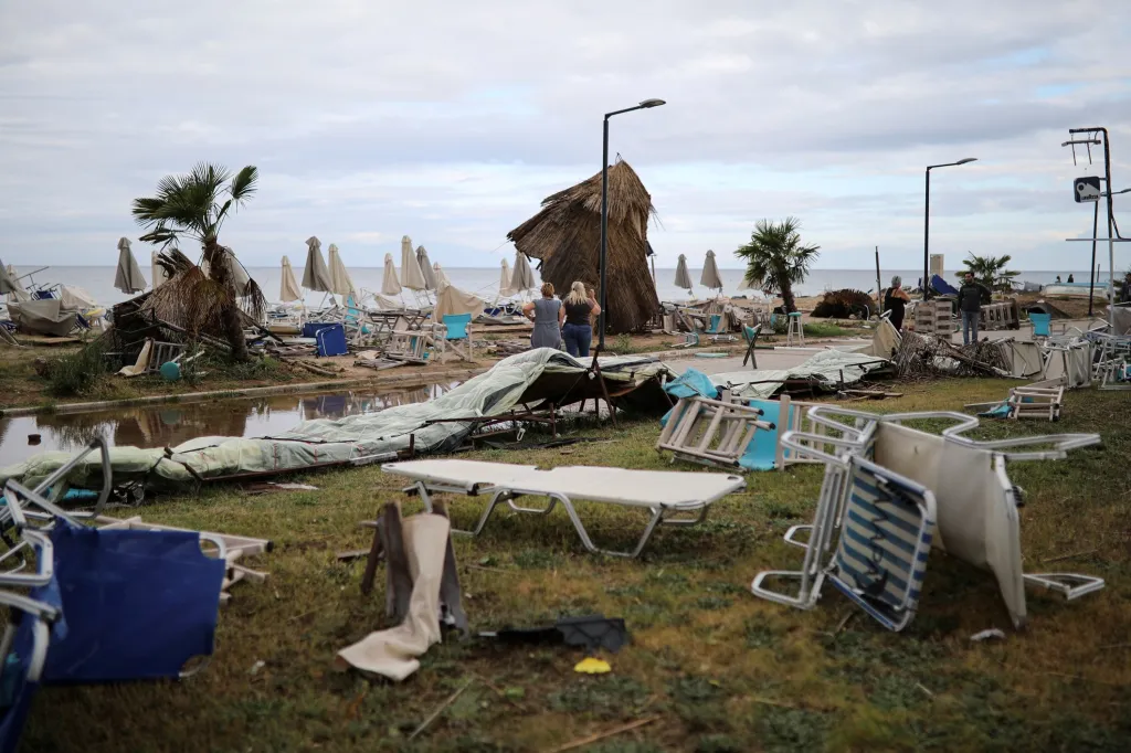 Lidé stojí mezi troskami na pláži v obci Nea Plagia v Řecku po silných bouřích