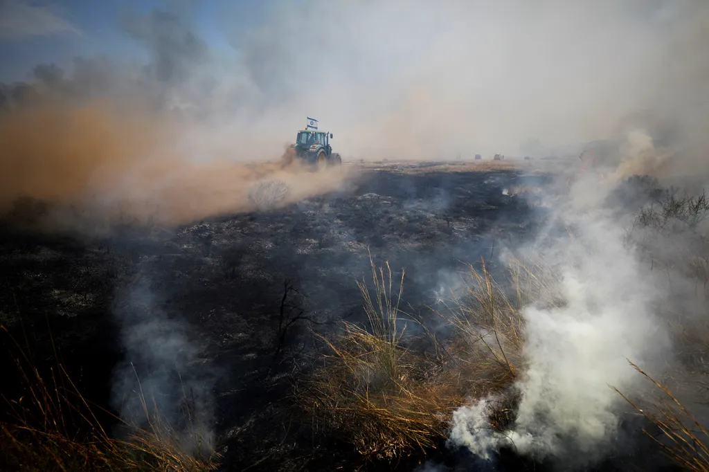 Traktor uprostřed spálené krajiny a dýmu v oblasti, kde Palestinci svými létajícími zápalnými draky, které vypouštějí na izraelské území z hraničních oblastí Gazy, způsobili několik rozsáhlých požárů