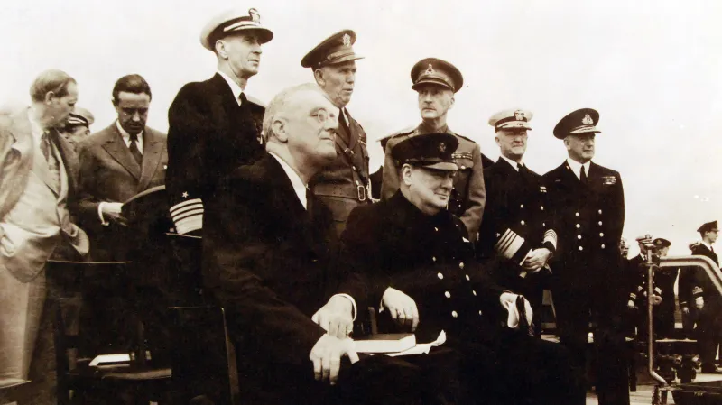 Americký prezident Franklin Delano Roosevelt (sedící vlevo) a britský premiér Winston Churchill (sedící vpravo) na snímku ze srpna 1941 na palubě britské válečné lodi HMS Prince of Wales