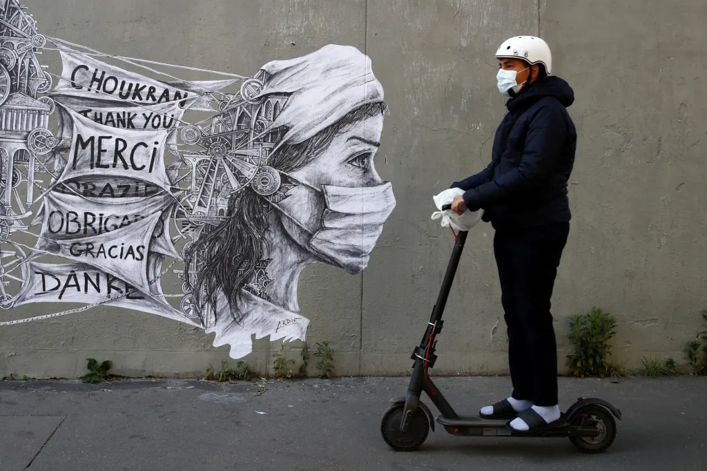 Muž na elektrické koloběžce projíždí kolem nástěnné malby pouličního umělce Ardifa v Paříži