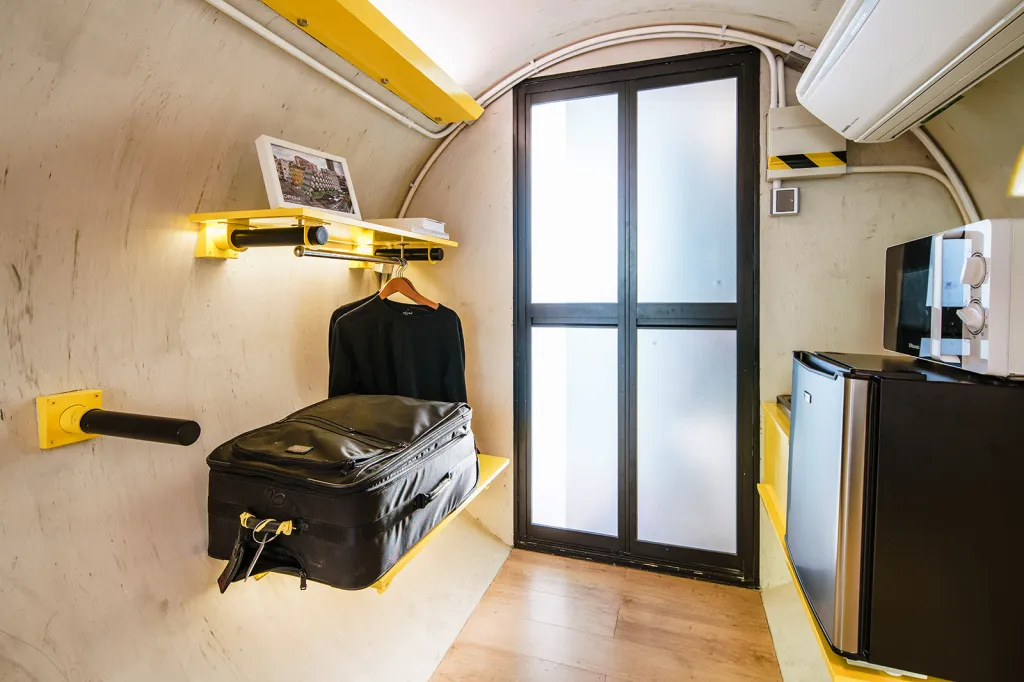 Interiér jednotky OPod se sklápěcími policemi, ledničkou, mikrovlnkou a vstupem do koupelny