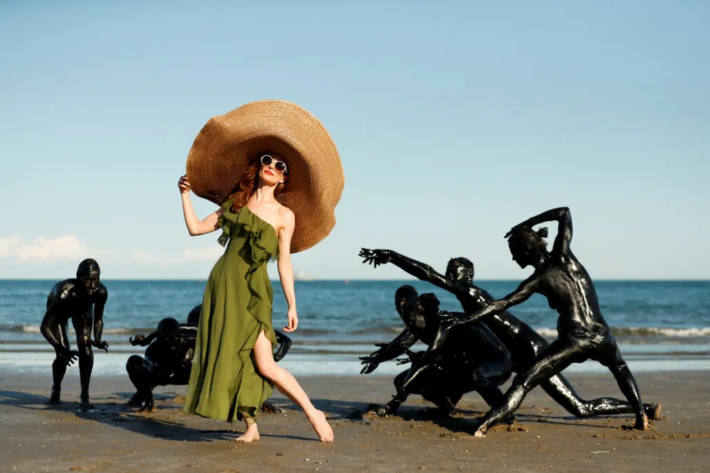 Herečka Lotte Verbeeková pózuje s tanečníky na pláži během filmového festivalu v Benátkách. Letošní ročník musel být divácky limitovaný kvůli covidovým opatřením, zato historicky se konal již po 77