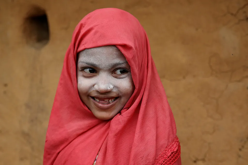 Rohingská dívka se usmívá poté, co si na obličej nanesla tradiční tanaka pastu v uprchlickém táboře Kutupalong v bangladéšském městě Cox's Bazar.