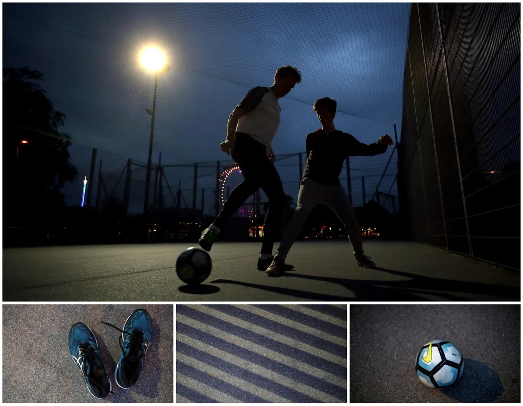 Teenageři při večerním fotbalu na uměle osvětleném hřišti nedaleko ruského kola v ulicích Vídně