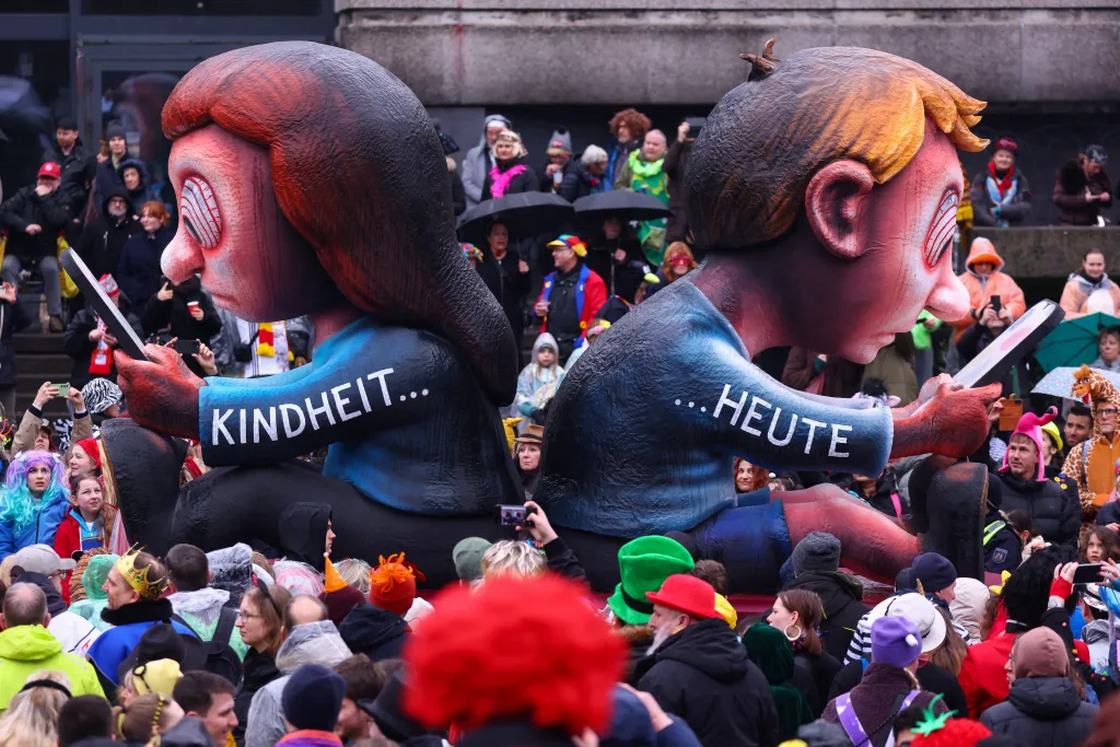 Karnevalový vůz zobrazující děti závislé na chytrých telefonech se slovy Dětství a Dnes