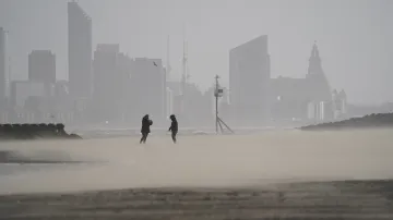 Lidé odolávají silnému větru na pláži v Brightonu
