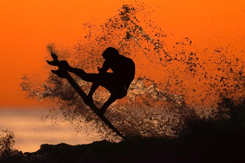 Jeden ze surfařů si užívá vln po západu slunce v Cardiffu v Kalifornii
