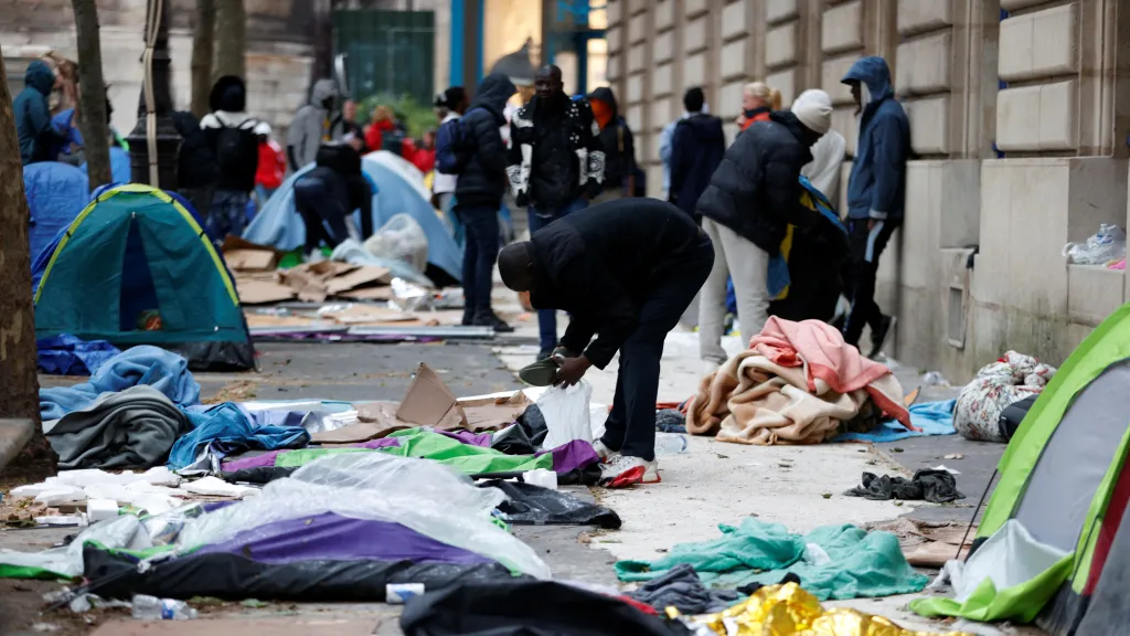 Migranti si sbírají své věci u stanů během vyklízení tábora na náměstí Saint-Gervais poblíž pařížské radnice