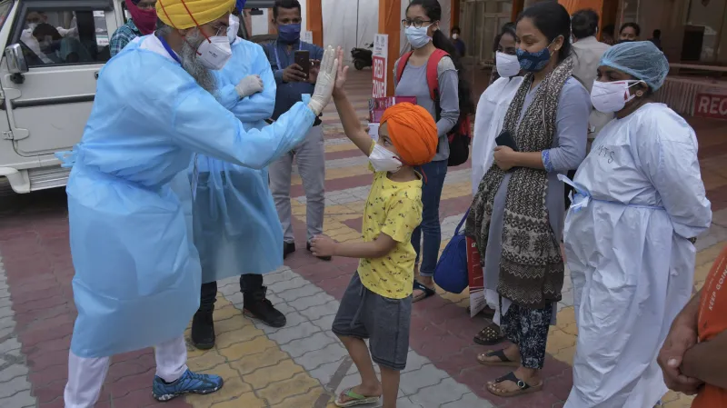 Zdravotnický pracovník se loučí se sedmiletým chlapcem Rudruem Singhem a jeho rodinou, kteří po covidu opouštějí izolační centrum