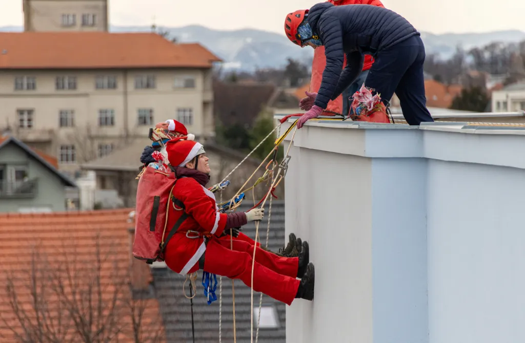 Dobrovolníci v kostýmech Santa Clause slaňují ze střechy dětské nemocnice v chorvatském městě Srebrnjak