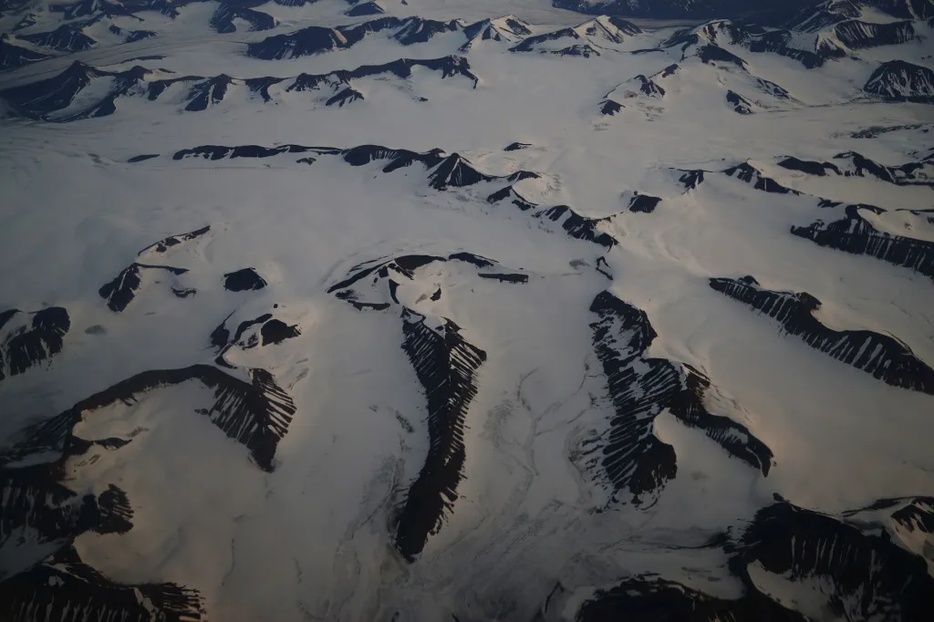 Letecký pohled ukazuje zasněžené hory na Špicberkách