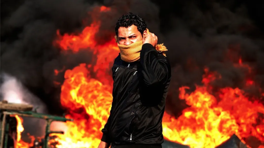 Demonstrant před hořící barikádou v Káhiře