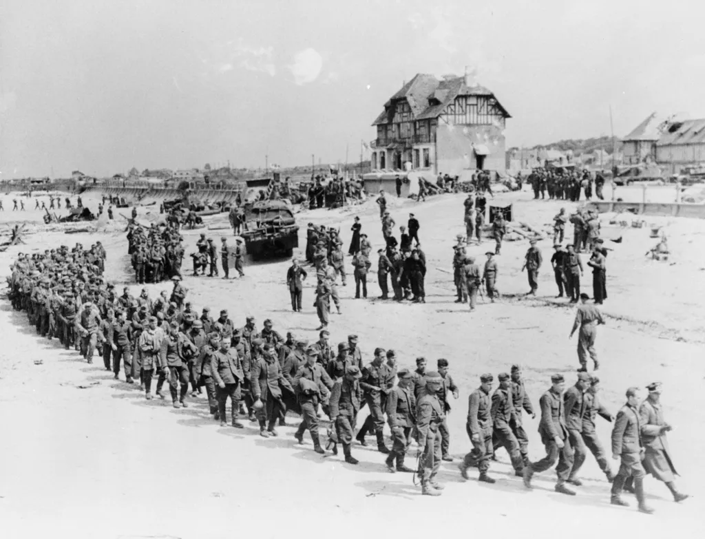 Pochod německých válečných zajatců podél pláže Juno k lodi, která je odveze do Anglie poté, co byli zajati kanadskými vojsky u Bernieres Sur Mer
