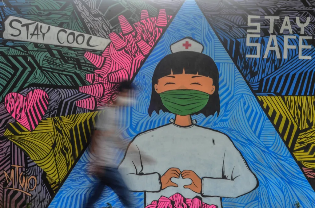Osoba míjí nástěnnou malbu zobrazující zdravotní sestru v místě zvaném Ciamis, na Západní Jávě v Indonésii
