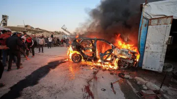 Lidé stojí poblíž hořícího vozidla po izraelském útoku, při kterém podle zdravotníků zahynul novinář stanice al-Džazíra Mohammad Wišáh
