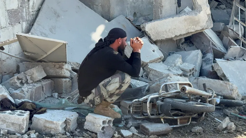 Muž sedí na troskách po izraelském náletu v Bajt Džin, Sýrie, 28. listopadu 2025