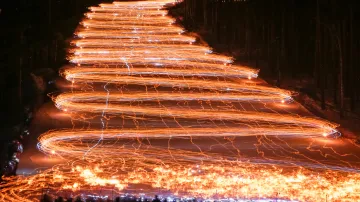 Stovky lyžařů a snowboardistů sjíždějí ze svahu s pochodní v ruce v sibiřském městě Železnogorsk.