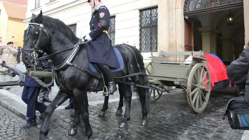Lafeta historické houfnice tažená koňským šestispřežím vyjíždí z bran kasáren Hradní stráže.