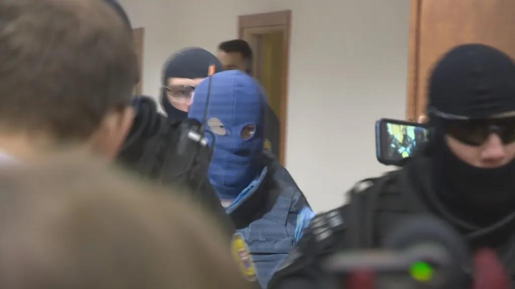 Zoltán Andruskó (v modré kukle) je přiváděn k soudu