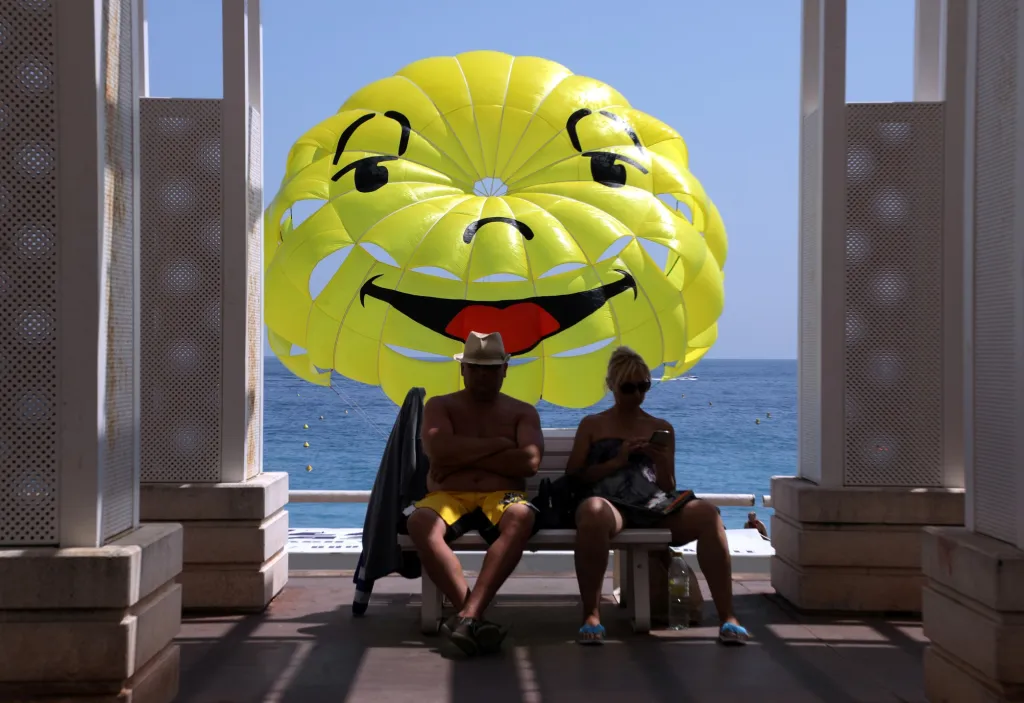 Letní sezona je v plném proudu a takto si ji užívají lidé na Promenádě des Anglais v Nice. Smajlík za nimi je startující padák na parasailing