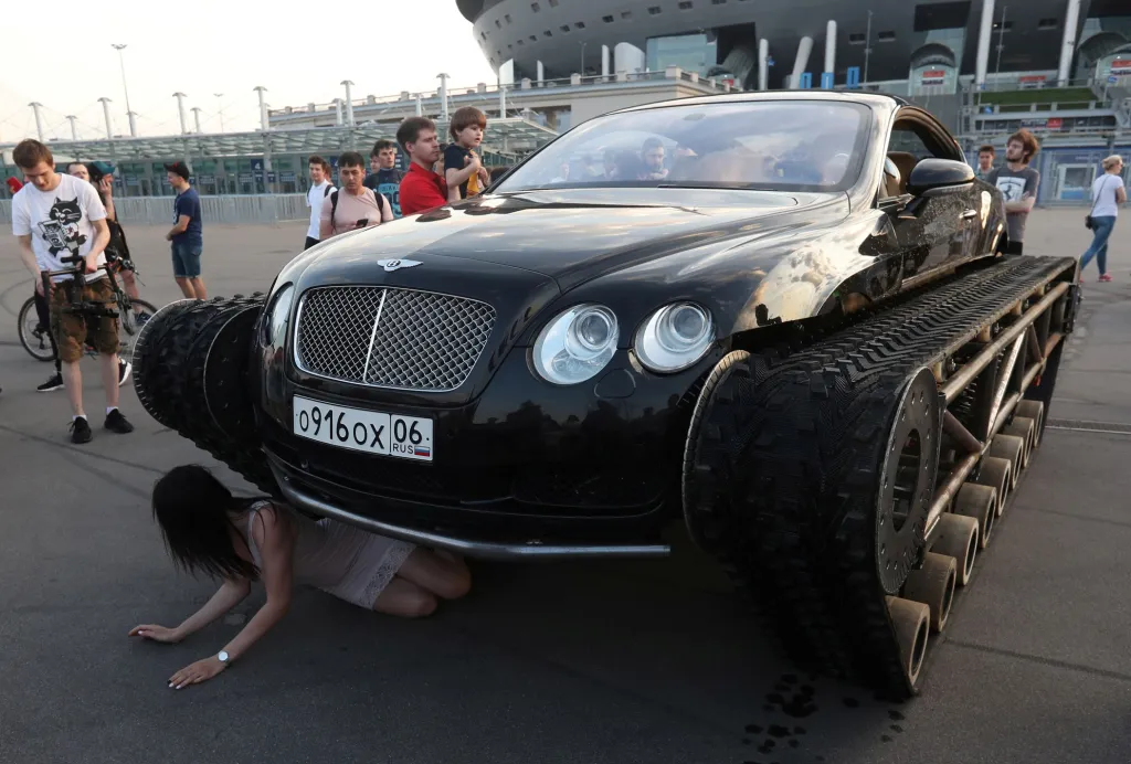 Žena nezvykle pózuje s vozem Bentley Continental GT upraveným na pásové vozidlo, které bylo vyrobeno ruskými automobilovými nadšenci, během přehlídky aut v Petrohradu