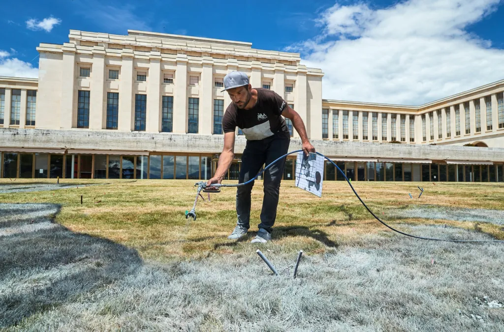 Saype připravuje graffiti zobrazující dvě děti, které spolu kreslí strom. Dílo vzniklo v červnu 2020 v Ženevě u příležitosti 75. výročí založení Organizace spojených národů