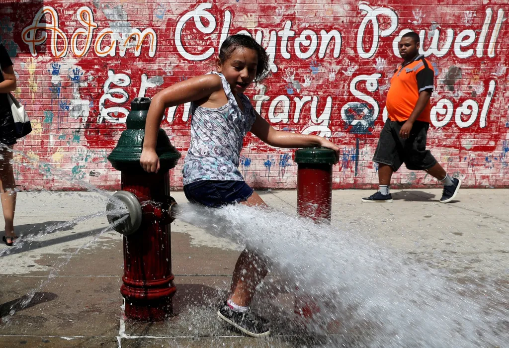 Dívka se chladí ve vodě z otevřeného požárního hydrantu během červencové vlny veder v New Yorku