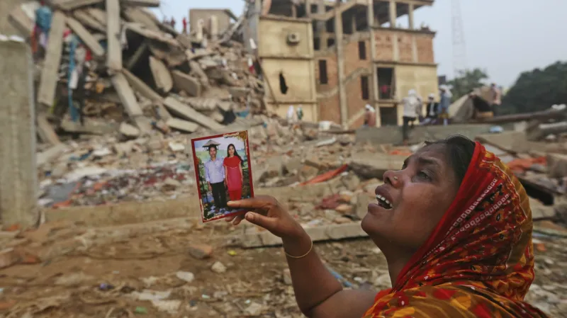 Žena čeká před troskami budovy na zprávy o svých příbuzných