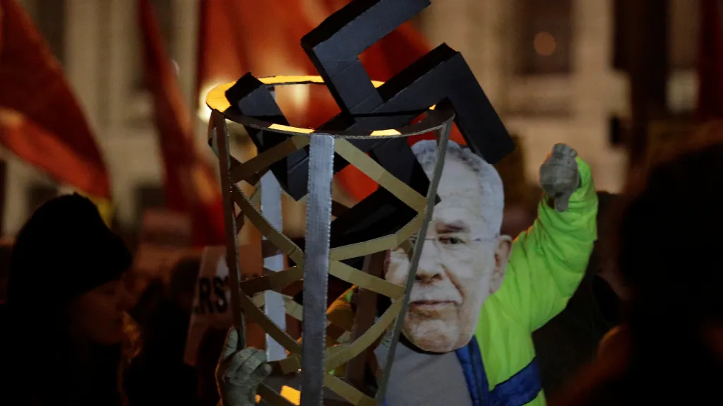 Demonstrant s maskou prezidenta Van der Bellena a s hákovým křížem v odpadkovém koši