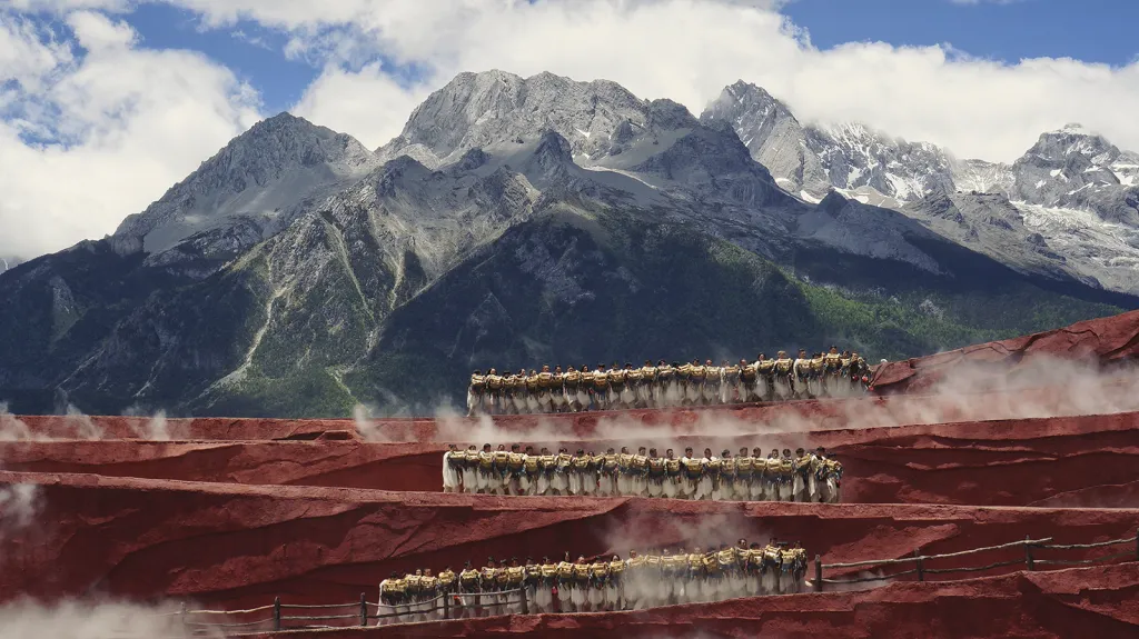 Tanec na úpatí hory Yulong (kategorie Krajina). „Čekala jsem čtyři dny na jasný den na úpatí hory Yulong. Bylo to úžasné, když místní lidé tančili na červeném pódiu před zasněženými vrcholky hor.“