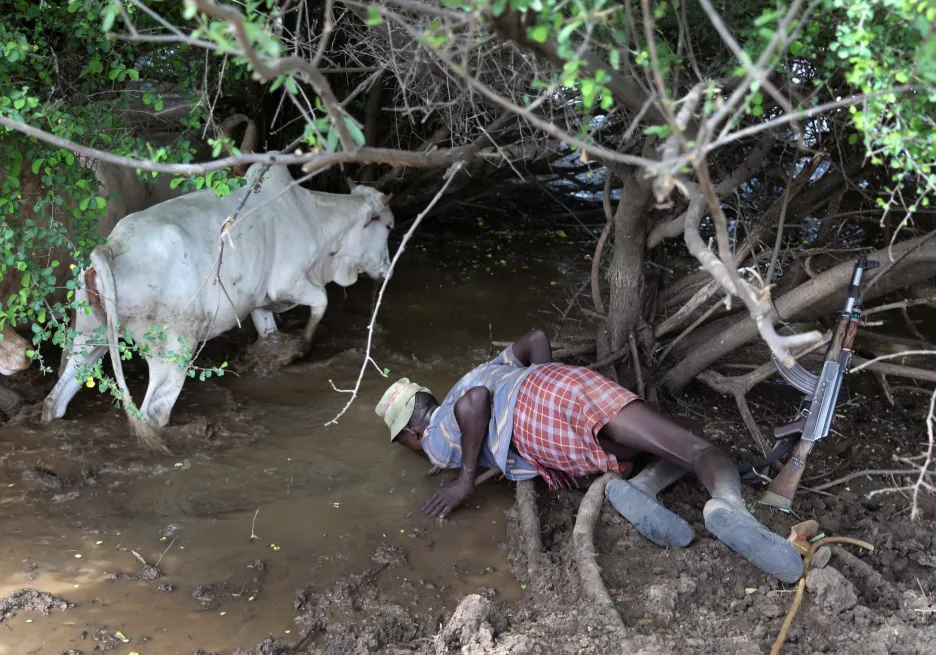 Turkanský bojovník pije vodu z bažiny, která chrání dobytek před válečníky z kmene Nyangatomu