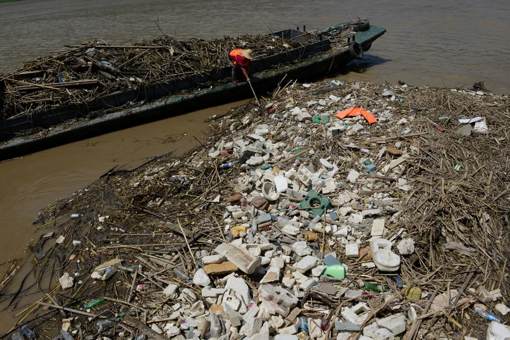Dělník sbírá odpadky na břehu čínské znečištěné řeky Jang-c'-ťiang