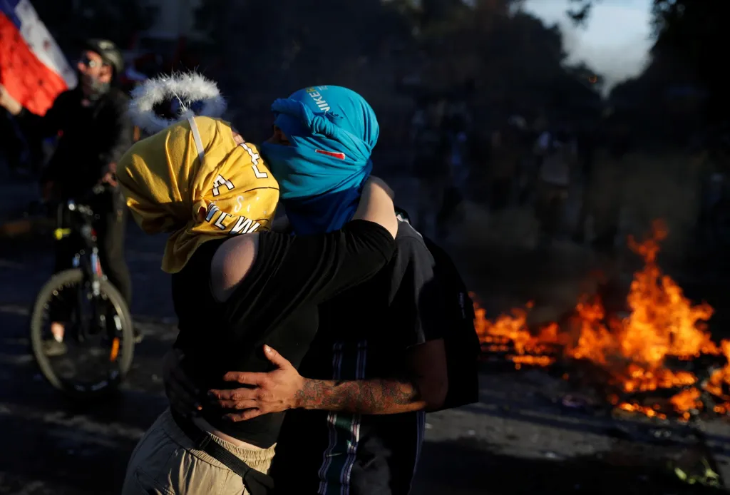 Během říjnových protivládních demonstrací v chilském Santiagu se líbá maskovaný pár