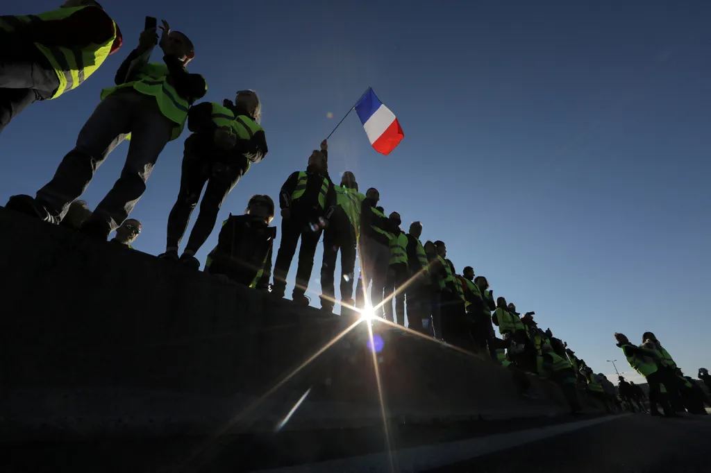 Lidé s reflexními vestami, symbolem francouzských řidičů, protestují proti navyšování cen pohonných hmot a blokují silnici ve městě Antibes.