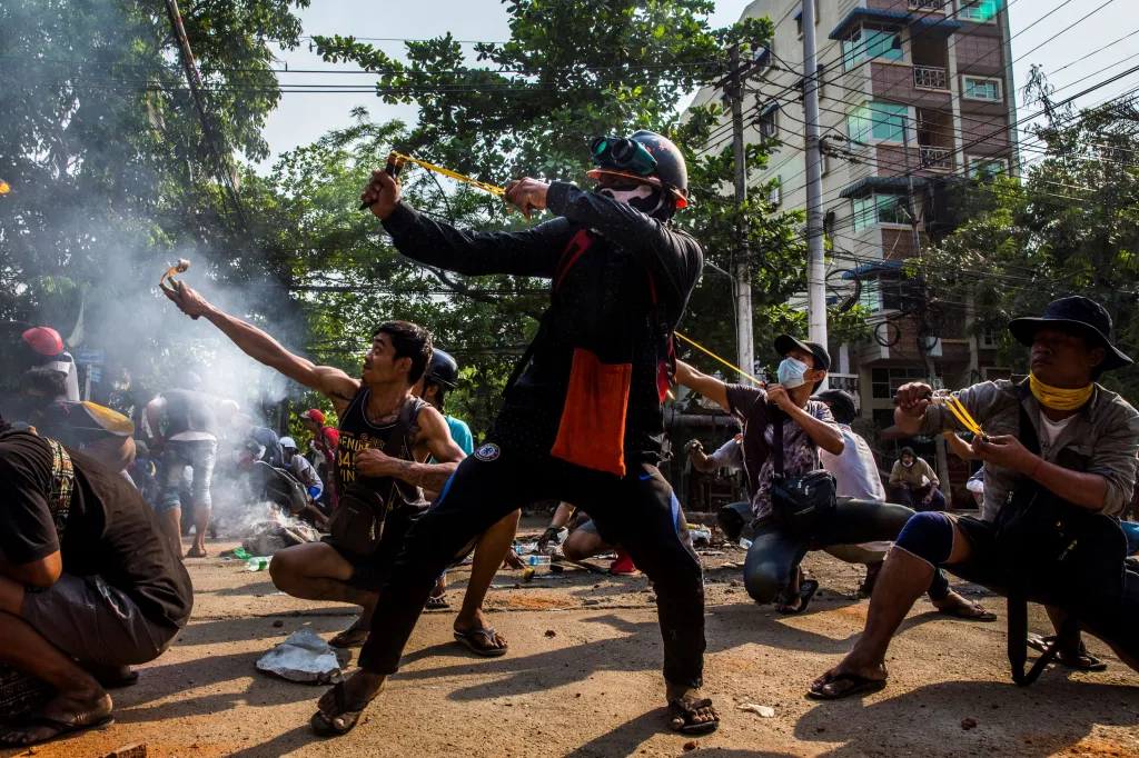 Vítězná fotografie v kategorii Jihovýchodní Asie a Oceánie – singles (jednotlivé). Demonstranti při střetu s bezpečnostními silami v Yangonu v Myanmaru používající praky a další podomácku vyrobené zbraně