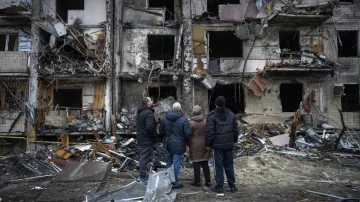 Lidé stojí před zničeným domem po útoku na Kyjev