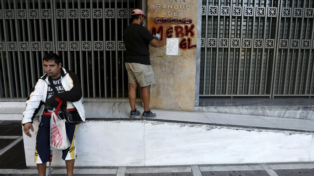 Dělník čistí graffiti na stěně řecké centrální banky