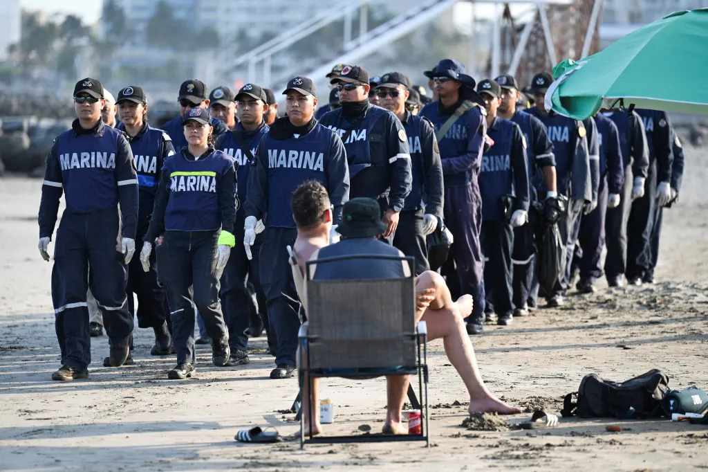 Turisté pozorují členy mexického námořnictva, kteří dorazili na pláž Caracol hledat černé dehtové skvrny. Místní obyvatelé se obávají, že se na pláž mohla vyplavit další ropa téměř měsíc poté, co byly ve státech Veracruz a Tabasco v mexickém Boca del Rio zjištěny první známky kontaminace