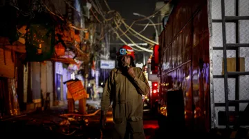 Hasič Surender Kumar (58 let) vychází z hořících obchodů s textilem ve staré čtvrti Nového Dillí (13. června 2024)
