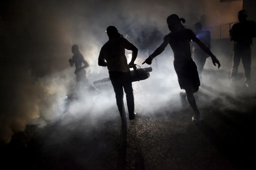 Na Haiti probíhá fumigační kampaň (uvolnění látek prostřednictvím kouře). Na fotografii pracovník ministerstva veřejného zdraví vypouští kouř v ulicích Port-au-Prince. Vládní činitelé se obávají rozšíření malárie, horečky dengue a onemocnění Zika v hlavním městě