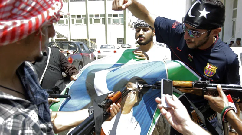 Libyjci míří na obrázek Muammara Kaddáfího