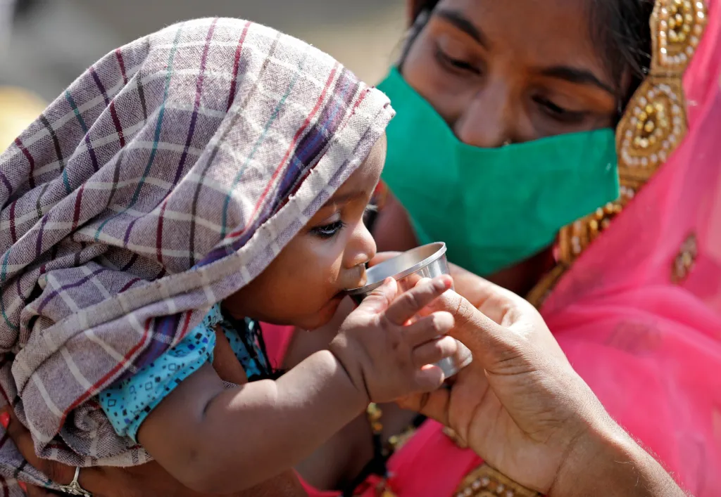 Matka nabízí pití dítěti během cesty z Kalkaty