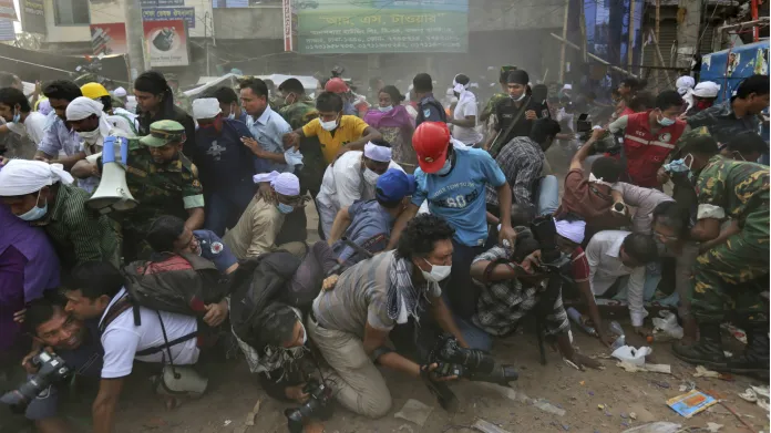 Novináři a přihlížející prchají z obavy před dalším pádem trosek od zřícené budovy