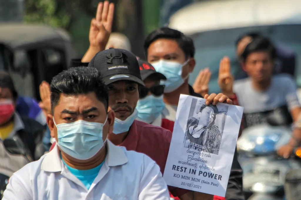 Demonstrant drží list, na kterém je zobrazena jedna z obětí represí bezpečnostních složek