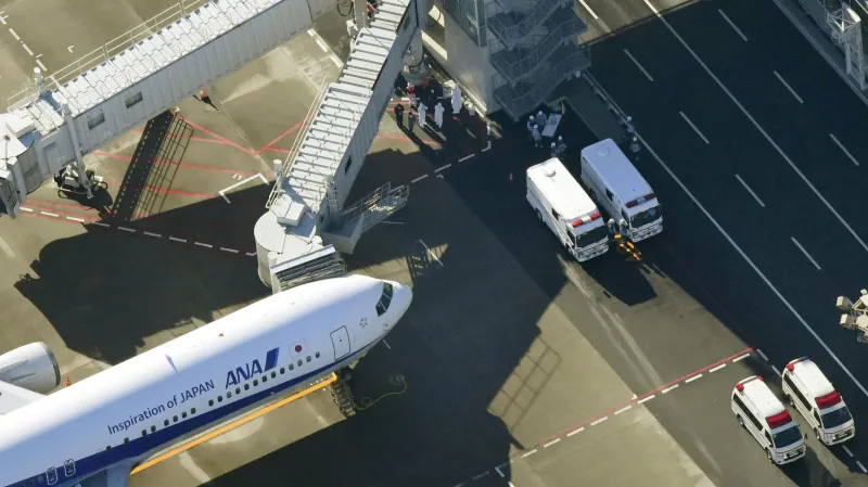 Zdravotníci v ochranných oblecích čekají na tokijském letišti na evakuované z Wu-chanu